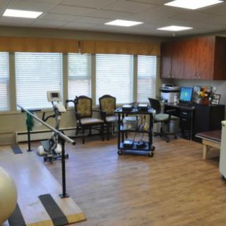 A physical therapy room equipped with exercise equipment and seating for patients.