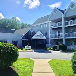 A sunny day view of a multi-story building with balconies and manicured landscaping.