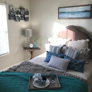 A cozy bedroom setup with pillows, a bed, and wall decor.