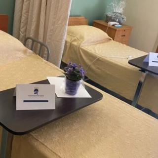 An empty hospital room with two beds and bedside tables.