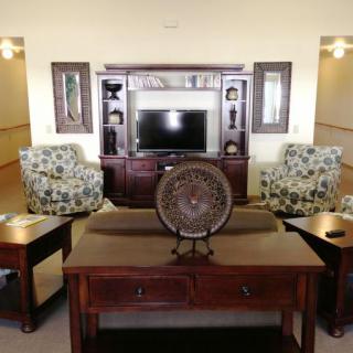 A cozy living room with floral armchairs, a wooden entertainment center, and decorative pieces.