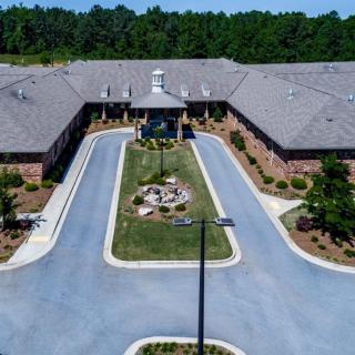 Aerial view of a large building with a circular driveway and landscaped entrance.