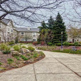 A serene garden pathway leading to residential buildings on an overcast day.