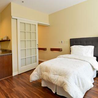 A cozy minimalist bedroom featuring a single bed with white bedding and sleek wooden flooring.