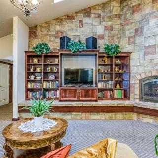 A cozy living room featuring a stone wall with built-in bookshelves, a television, and a fireplace.