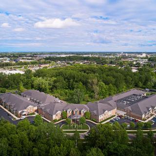 Aerial view of a building complex surrounded by trees and a clear sky.