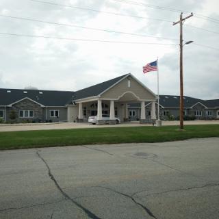 A single-story building with an American flag flying in front, set against a cloudy sky.