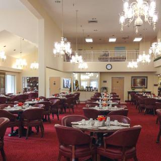 An elegant dining room with chandeliers, neatly arranged tables and chairs, and a warm ambiance.