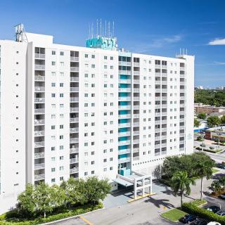 A tall hotel building with palm trees and a clear blue sky.