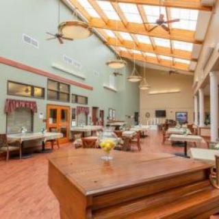 A spacious dining area with skylights and large windows, featuring multiple tables and ceiling fans.