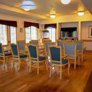 A well-lit conference room with arranged chairs and wood flooring.