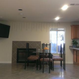 A cozy dining area with a table and chairs near a fireplace and a wall-mounted television.