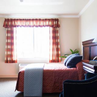 A cozy bedroom with a large window, bed, and stylish decor.