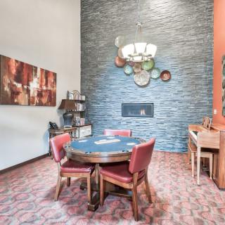 A stylish dining area with a central table and chairs, accented by a fireplace and a piano.