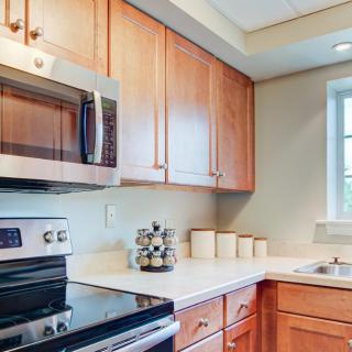 A modern kitchen with wooden cabinets, stainless steel appliances, and a bright window.