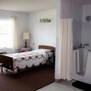 A simple, minimalist hospital room with a single bed and a curtained area.