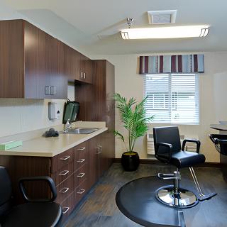 A modern hair salon with a stylish chair, a large mirror, and cabinetry for storage.