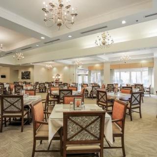 A spacious dining room with elegant chandeliers and neatly arranged tables and chairs.