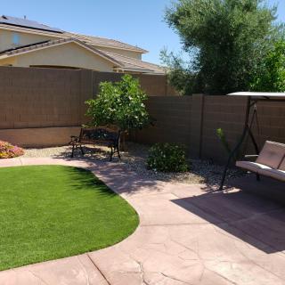 A tranquil backyard with a swing, bench, and artificial grass.