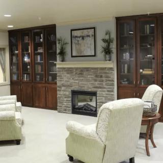 A modern living room with a fireplace, elegant bookshelves, and comfortable armchairs.