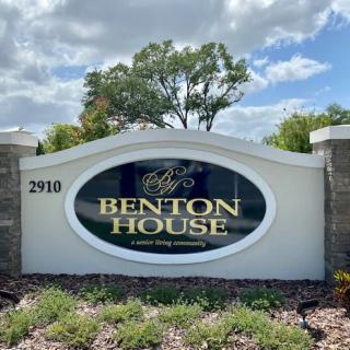 A sign for Benton House, featuring elegant landscaping and a clear blue sky.