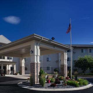 A hotel entrance with an American flag waving against a clear blue sky.