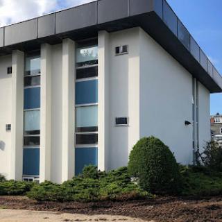 A modern building featuring large windows and a landscaped exterior.