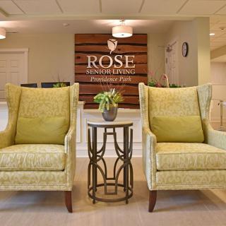A welcoming lobby area featuring two comfortable chairs and a wooden sign with the name 'Rose' on the wall.