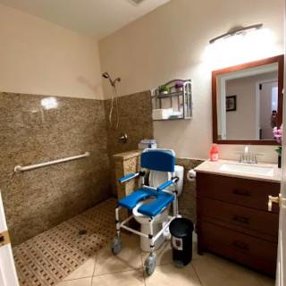 An accessible bathroom with a spacious shower area, equipped with a wheelchair and grab bars.