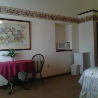 A cozy room with a small table, chair, and wall painting.