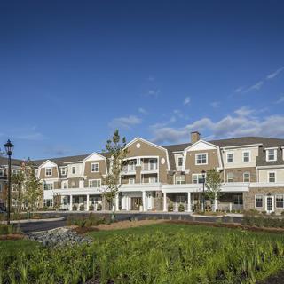 A three-story residential building with landscaping under a clear blue sky.
