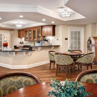 A cozy kitchen and dining area featuring elegant furnishings, warm lighting, and a wooden floor.