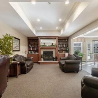 A cozy living room with a fireplace, leather chairs, and bookshelves.