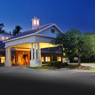 A beautifully lit hotel entrance at night with surrounding trees and a calm atmosphere.