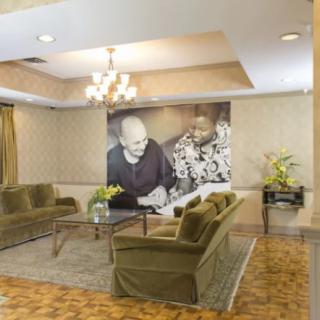A stylish lobby with comfortable seating and a large artwork displayed on the wall.