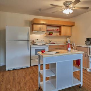 A modern kitchen with wooden flooring, featuring a refrigerator, stove, and a central island.