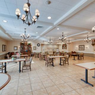 A spacious dining area with elegant chandeliers and neatly arranged tables and chairs.