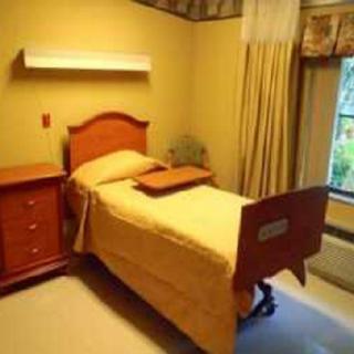 A cozy room with a single hospital bed and wooden furniture.