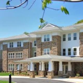 A modern residential building with a stone facade and large windows under a clear blue sky.