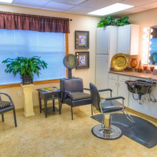 A cozy and well-decorated hair salon interior with chairs, a large mirror, and various decor items.
