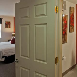 An interior view of a hotel room featuring an open door and wall artwork.