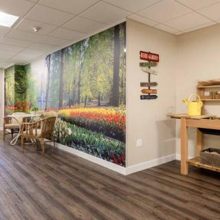 A cozy interior space featuring a nature-themed wall mural and seating area.