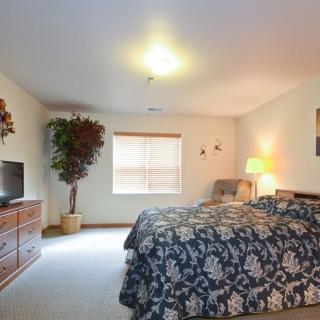 A cozy bedroom with a large bed, wooden furniture, and soft lighting.