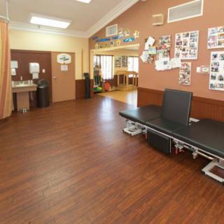 A spacious rehabilitation room in a clinic, equipped with treatment tables and exercise equipment.