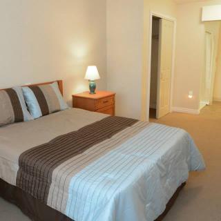 A cozy bedroom with a neatly made bed, bedside lamp, and simple decor.
