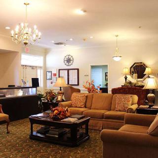 A cozy living room with a chandelier, sofas, and a reception desk.