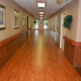 A well-lit hallway featuring wooden flooring and decorative artwork along the walls.