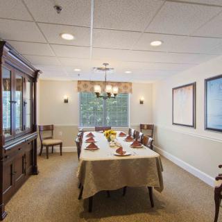 A formal dining room with a large table set for a meal, featuring a chandelier and classic decor.