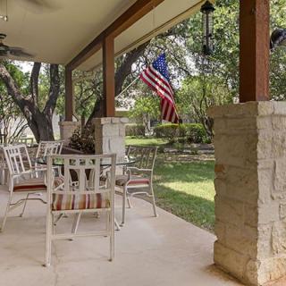 A cozy patio with outdoor furniture and a view of a garden, adorned with an American flag.
