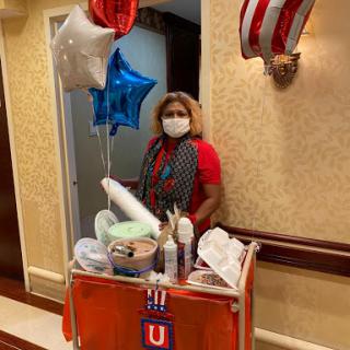 A vendor decorated with balloons stands beside her snack trolley, ready to celebrate.